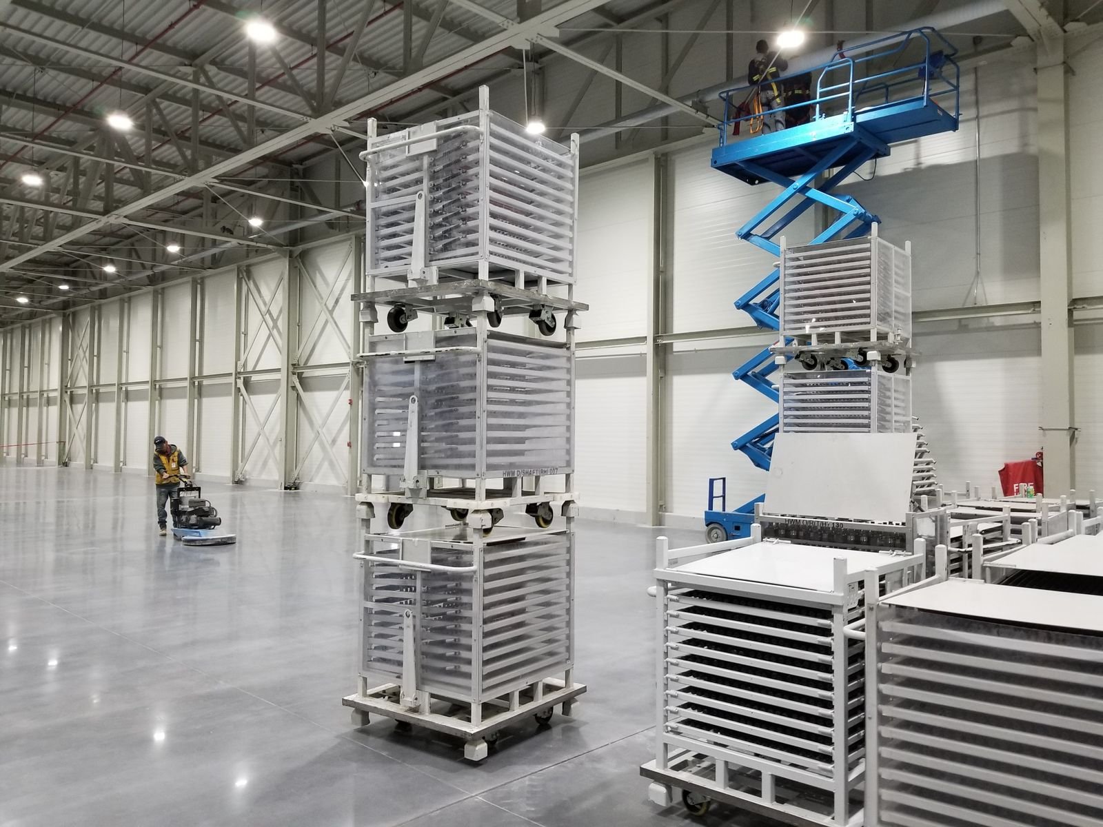 Racks metálicos y plataforma de elevación tipo tijera dentro de la nave