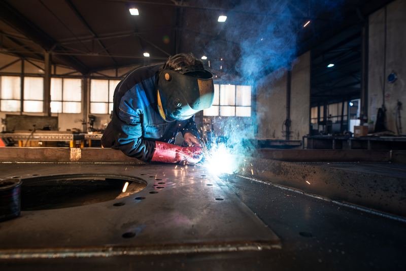 Soldador con careta trabajando entre chispas dentro de una nave