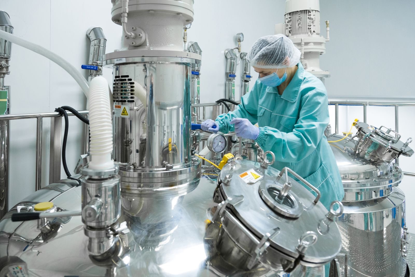 Técnica con cofia y bata operando reactores de acero inoxidable